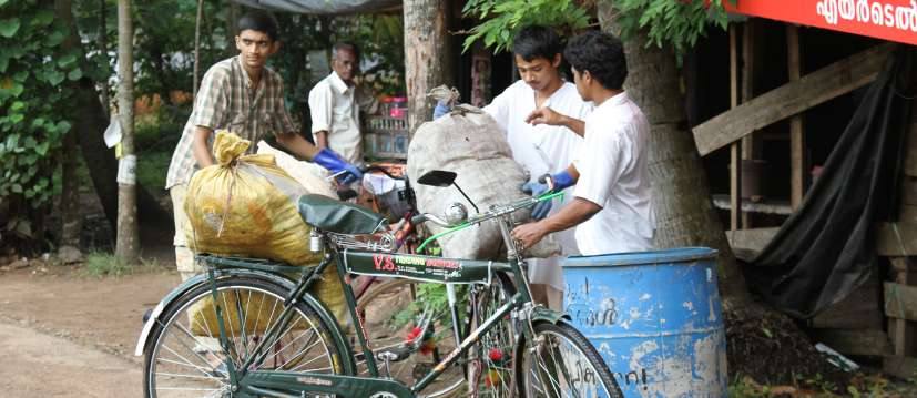 Volunteer with a bicycle beside waste bins