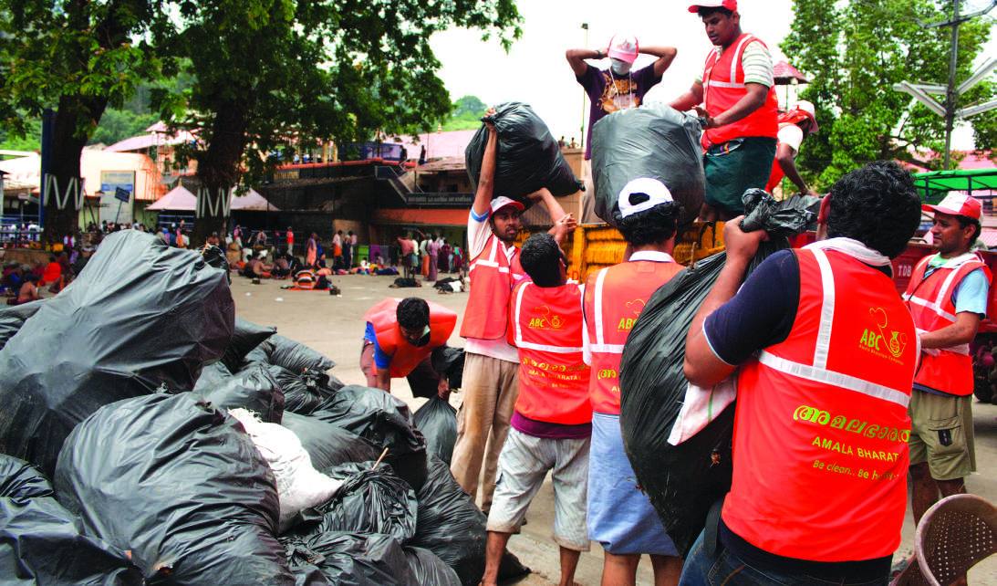 Volunteers in orange vests hauling sacks of waste