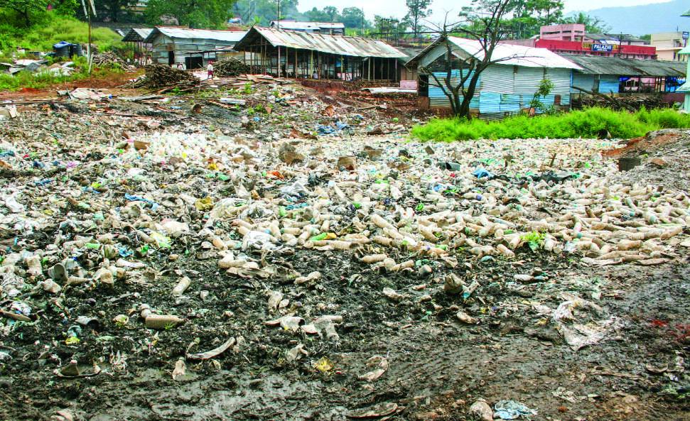Before: waste spread across a field near huts