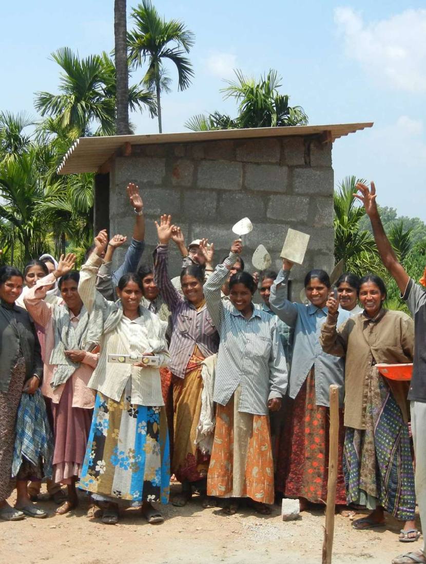 Women celebrating in front of a newly built toilet